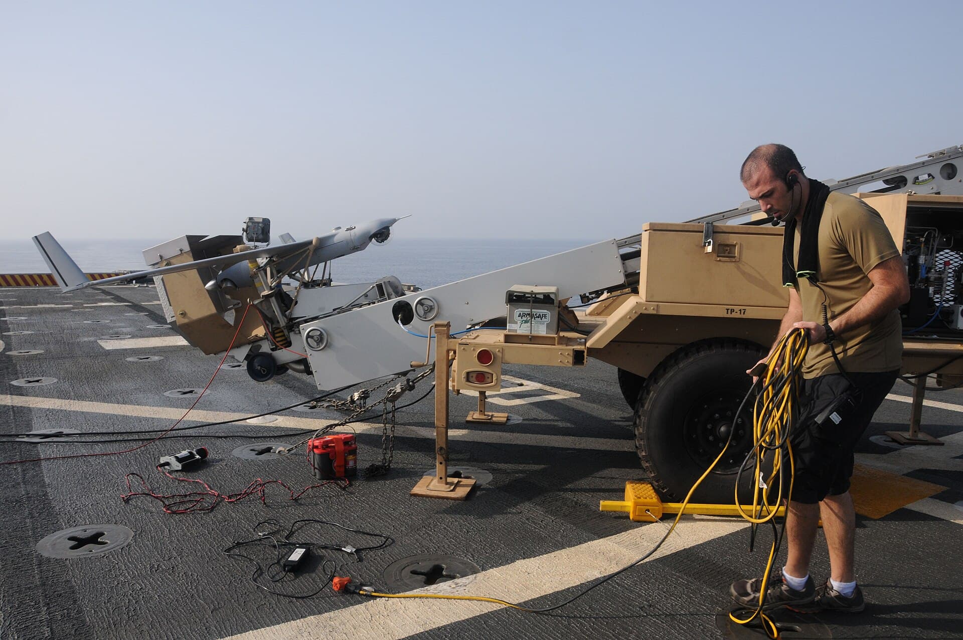 An engineer prepares equipment on a ship's deck